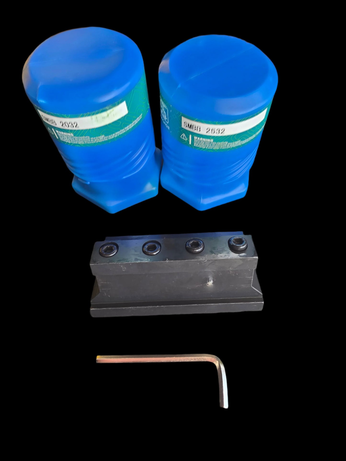 Two blue containers, a metal tool, and an Allen wrench on a dark surface.