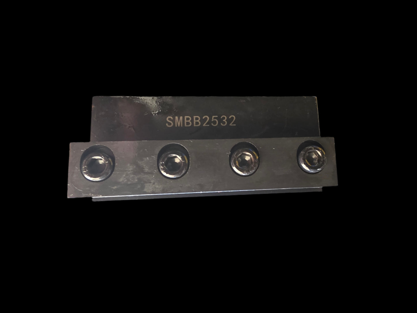 Metal component with four screws on a gray background